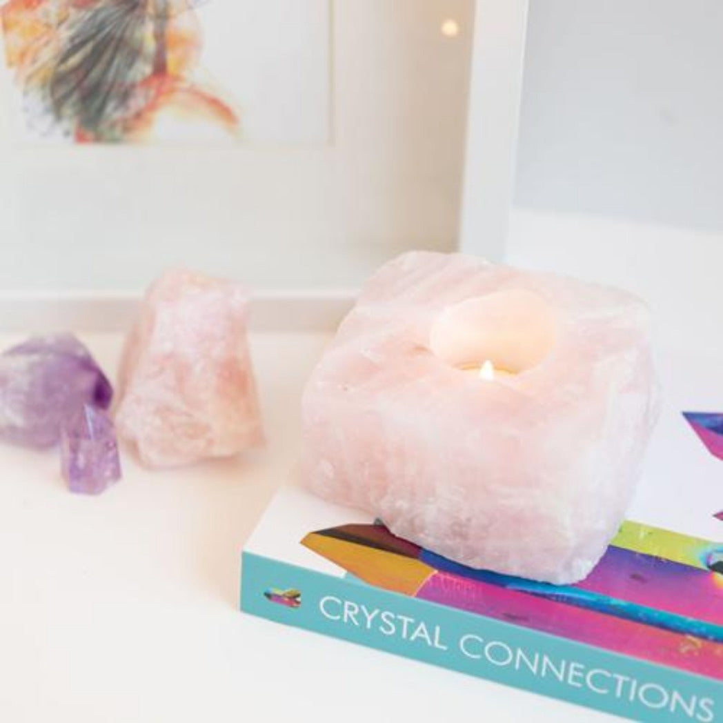 Candle Crystal Homewares Love Rose Quartz Rough Cut. Pale Pink Square cut rose quartz crystal . Sits on Crystal Connection Book from side view. Contains light tealight with amethyst and rose quartz in background