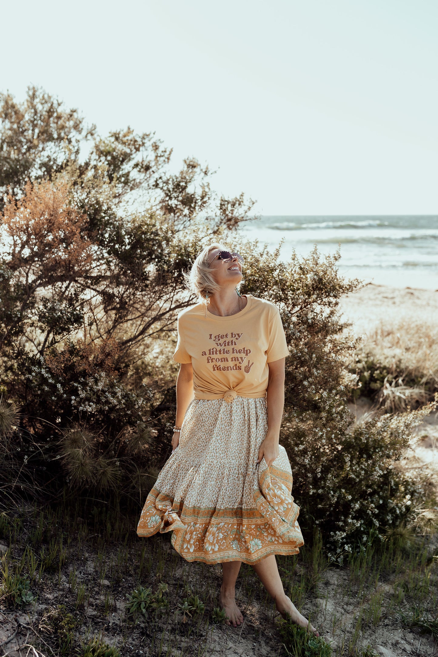 model wearing i get by with a little help from my friends in mustard paired with a flowy floral boho skirt mental health awareness