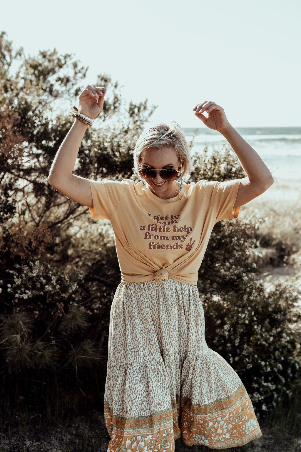 model wearing i get by with a little help from my friends in mustard paired with a flowy floral boho skirt mental health awareness