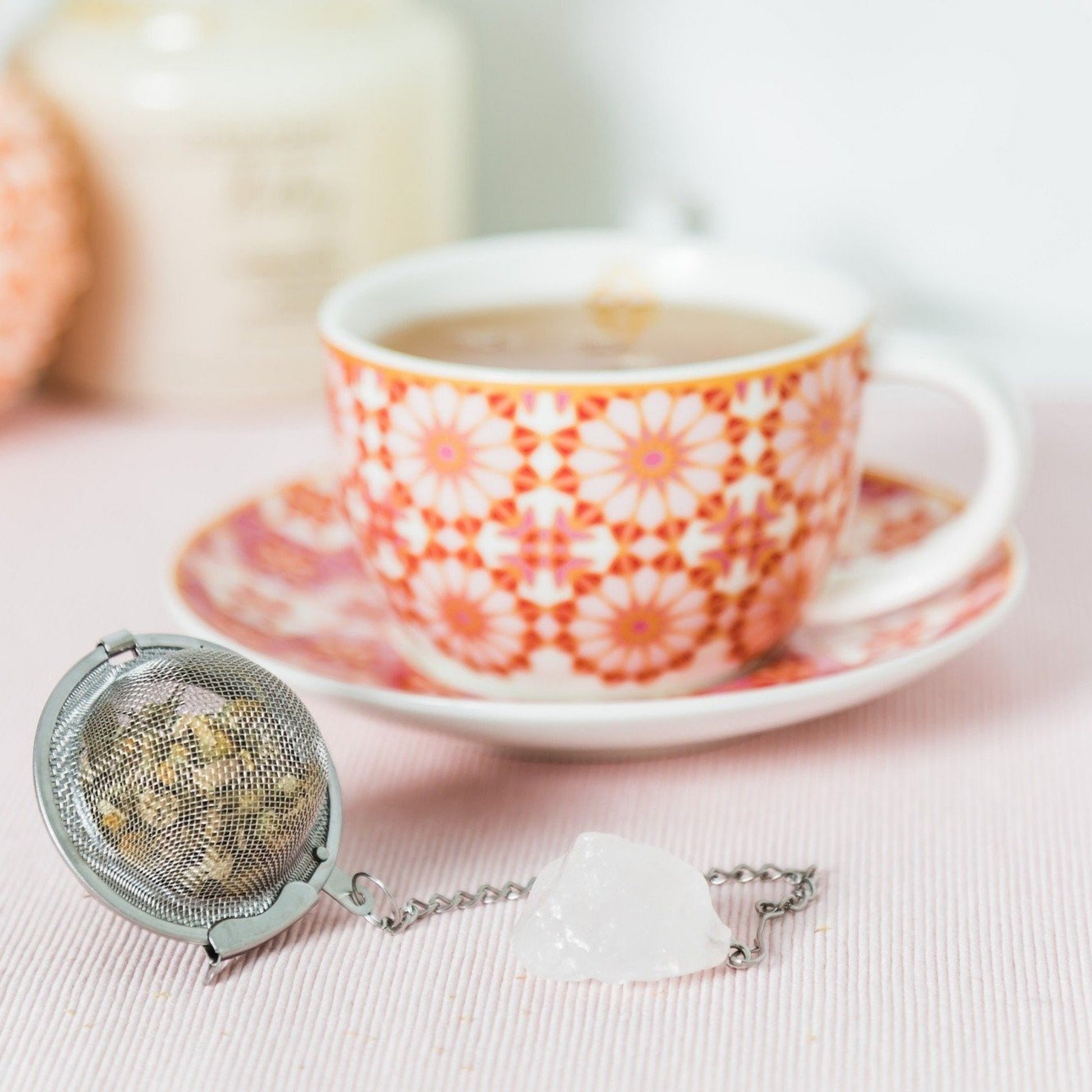stainless tea strainer with clear quartz stone beside teacup 