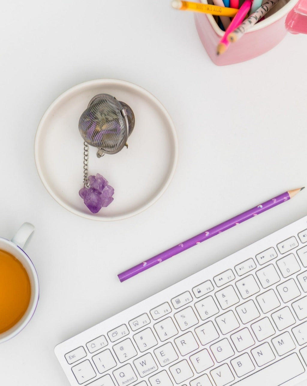 stainless tea strainer with Amethyst stone for dried flower tea and tea leaves displayed on office table with keyboard, teacup, and pencil holder