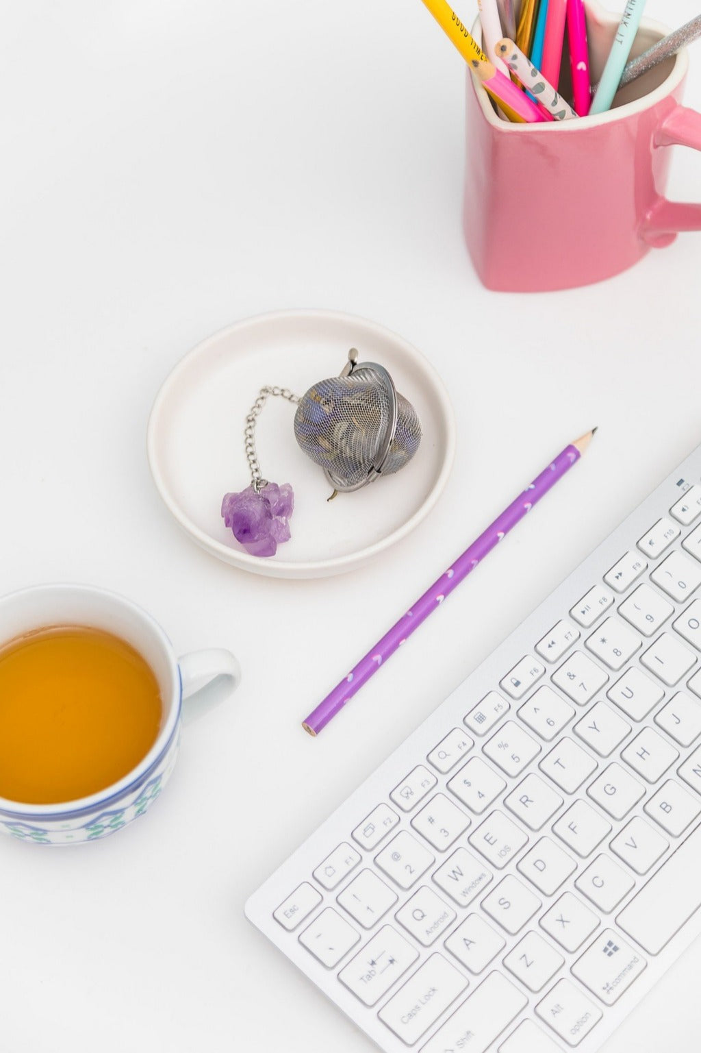stainless tea strainer with Amethyst stone for dried flower tea and tea leaves displayed on office table with keyboard, teacup, and pencil holder