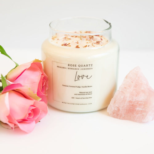 Candle Crystal Homewares Love Rose Quartz. Scent is Coconut, Caramel Fudge, Vanilla Bean. Candle is Glass, front on and on white background with pink roses and crystal 