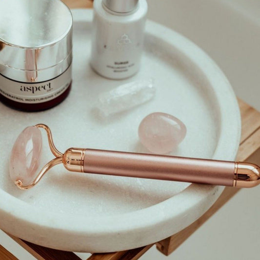rose quartz face roller in rose gold beside luxury beauty products