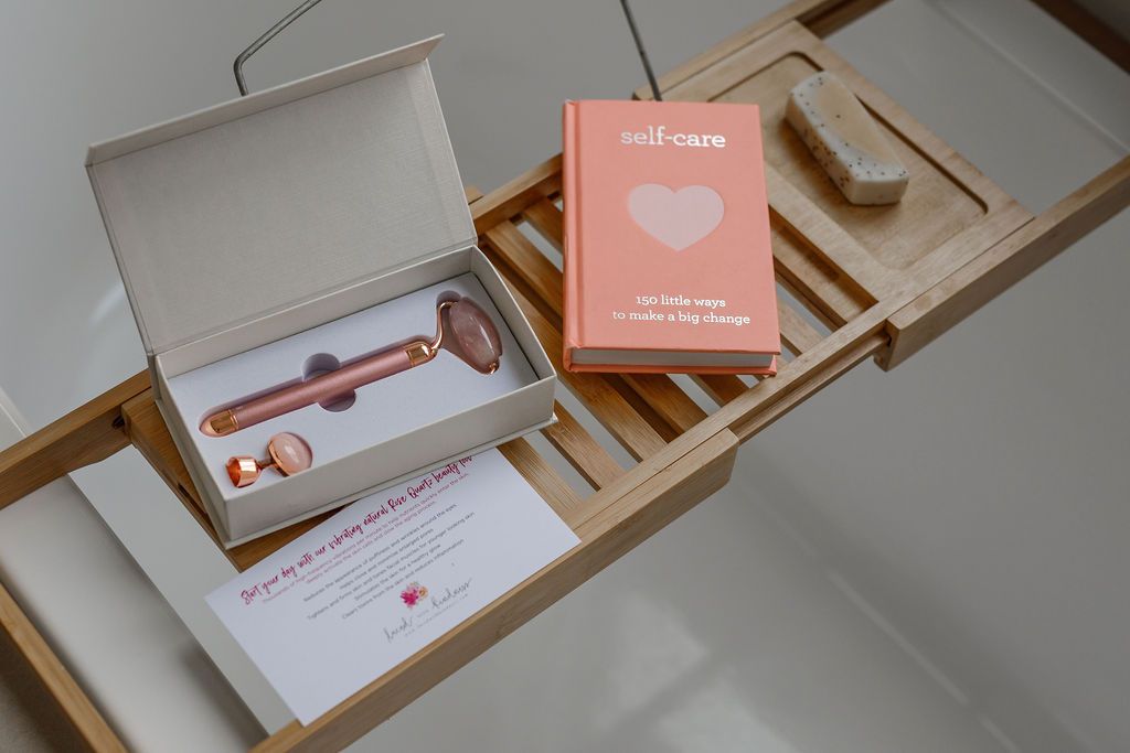 rose quartz face roller in box beside self care book