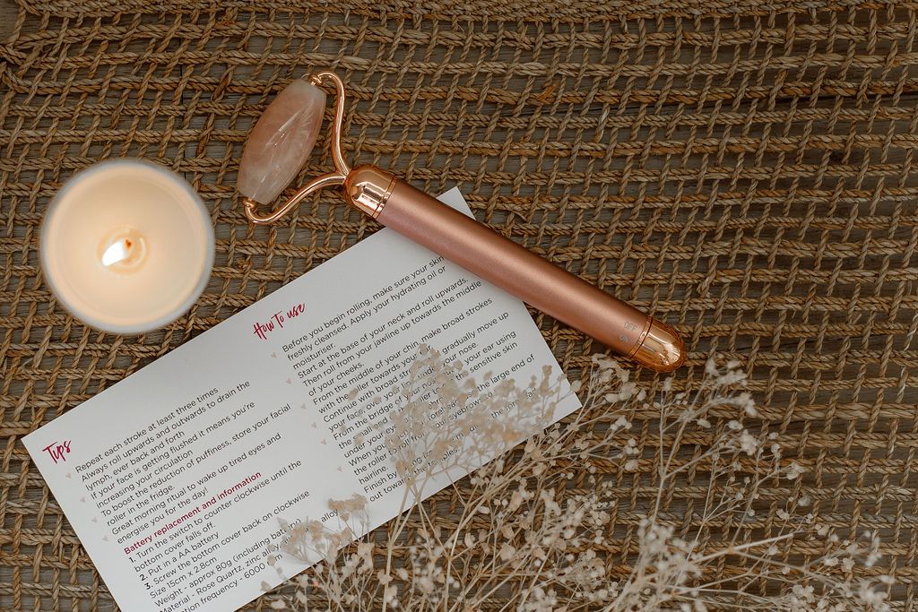rose quartz face roller in rose gold with lighted candle and how to use card