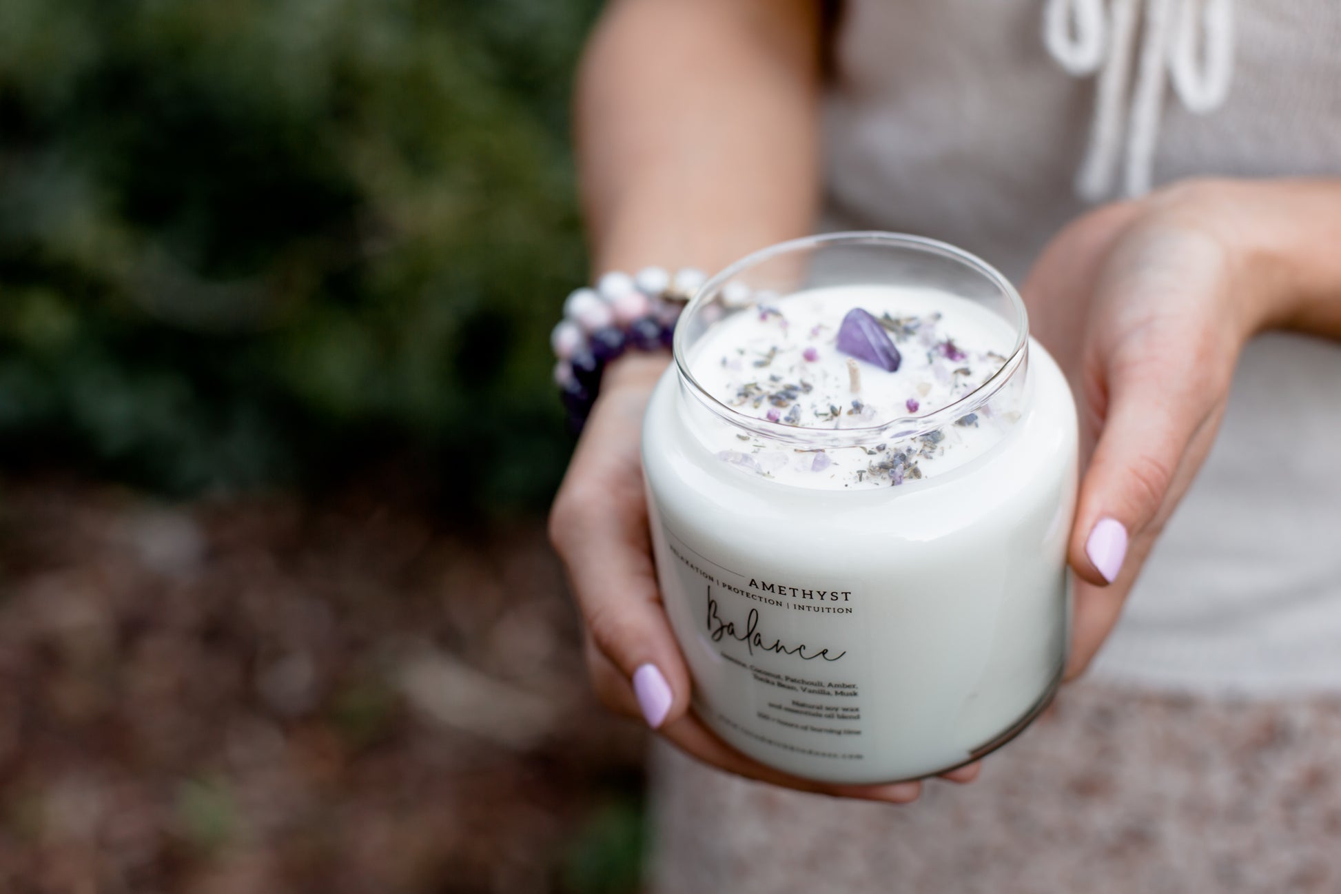 aroma healing candle in Balance with amethyst stones held by hands. Australian online candle store.
