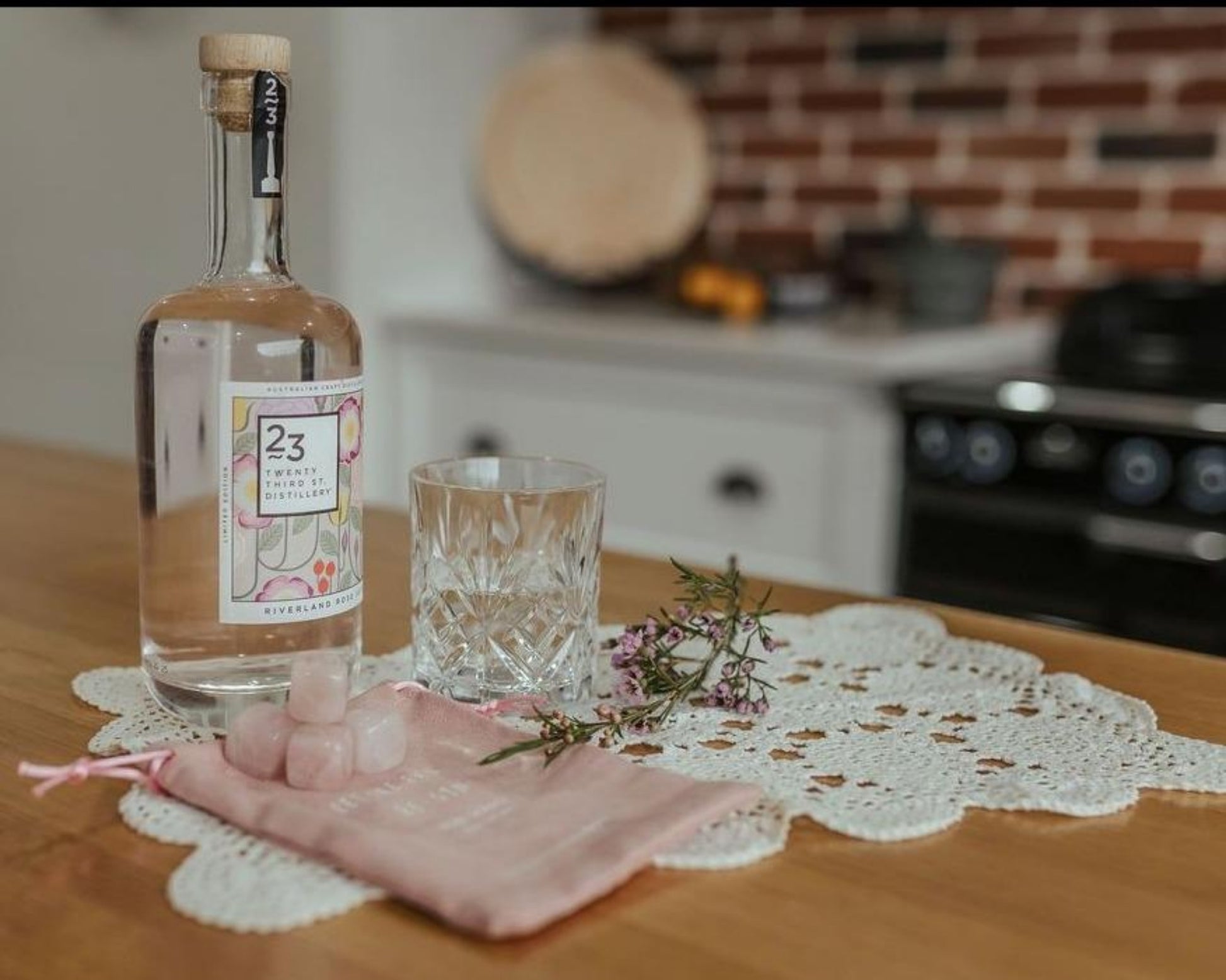 rose quartz gin stones and pouch displayed with a bottle of gin and glass