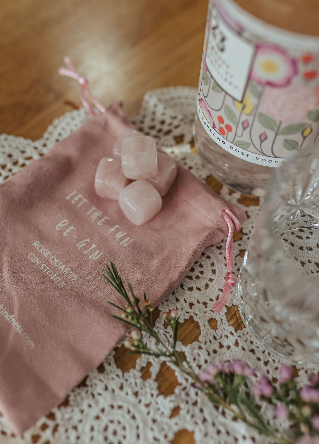 five rose quartz gin stones  displayed with pouch, gin bottle and glass in laced mantle