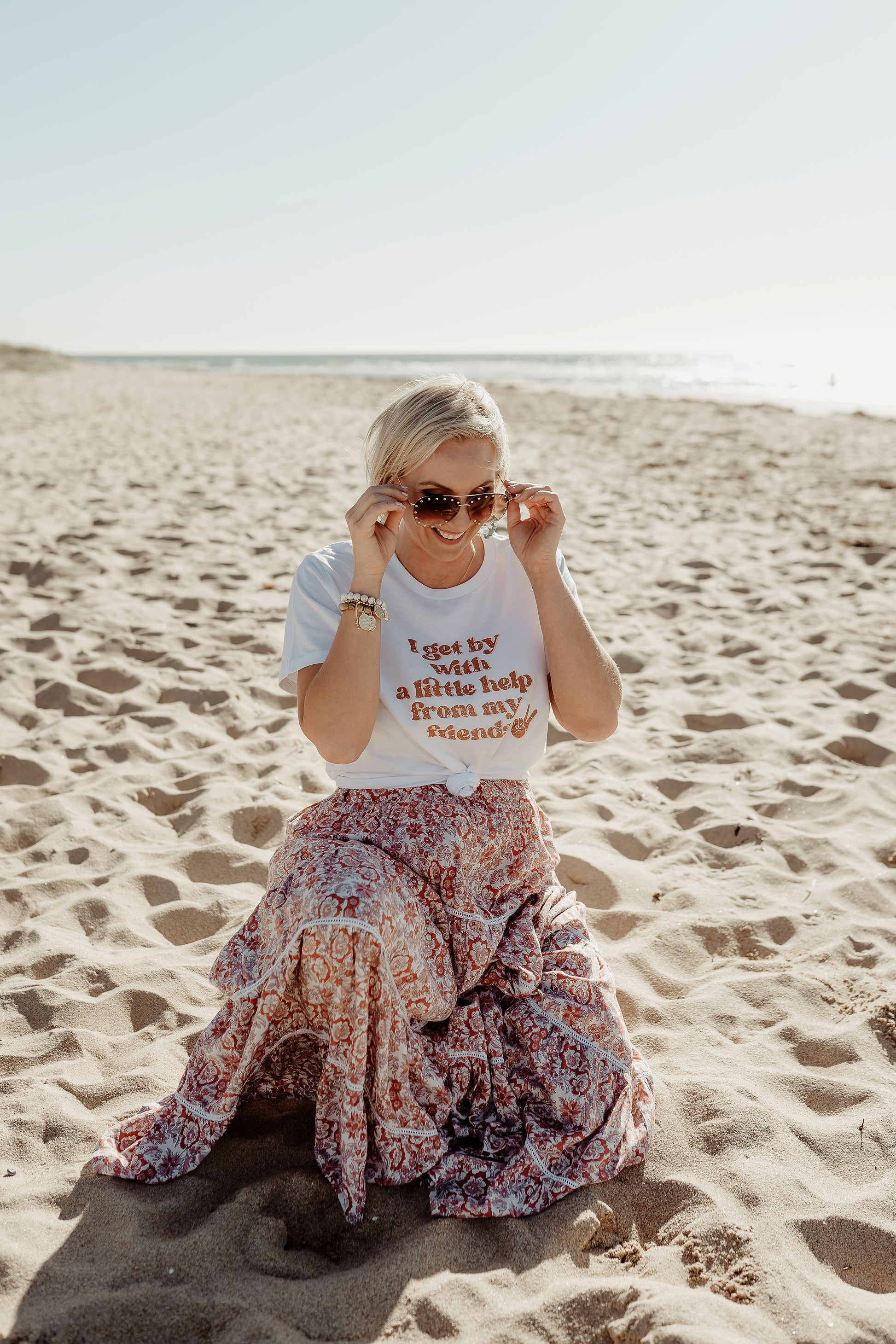 model posing at the beach wearing I get by with a little help with my friends t shirt in white paired with flowy boho skirt  mental health awareness