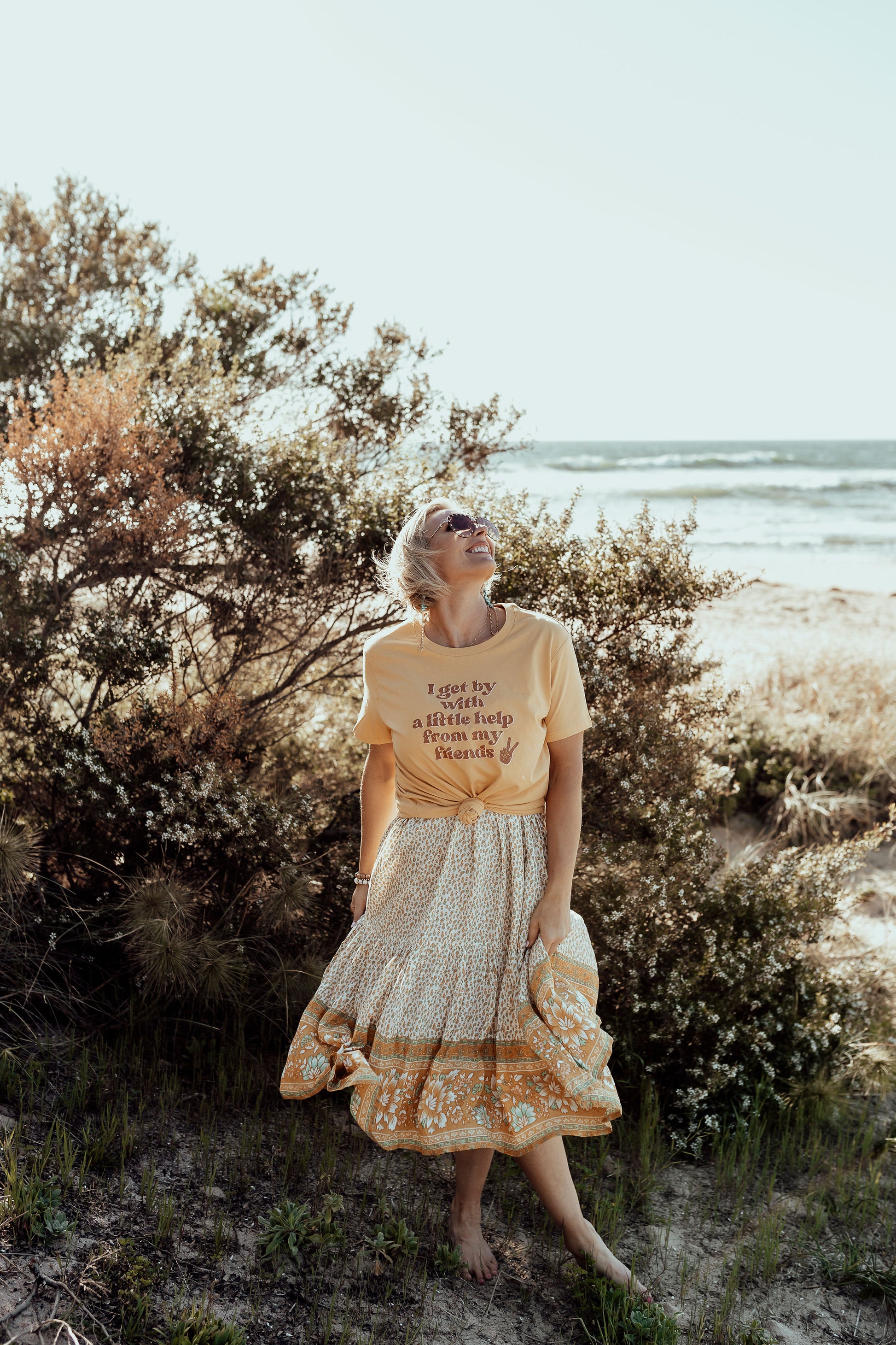 model wearing i get by with a little help from my friends in mustard paired with a flowy floral boho skirt  mental health awareness